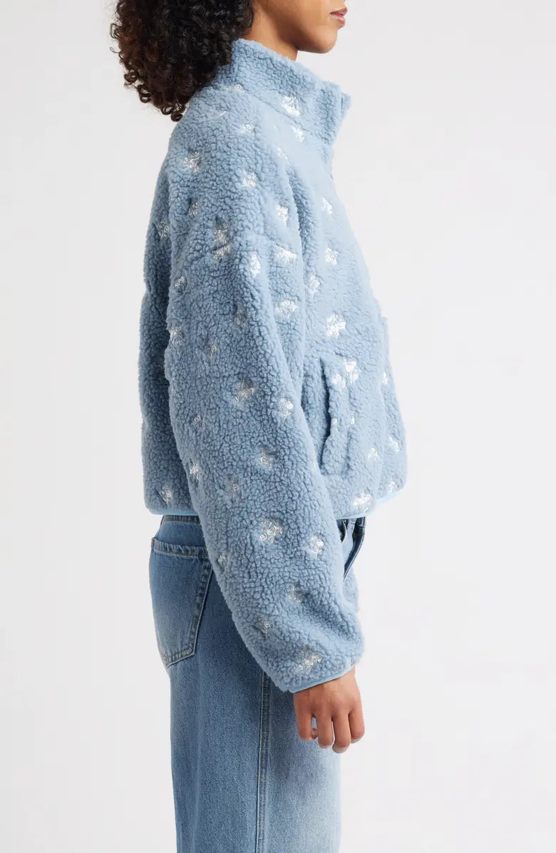 Person wearing a light blue fleece jacket with star patterns on a white background